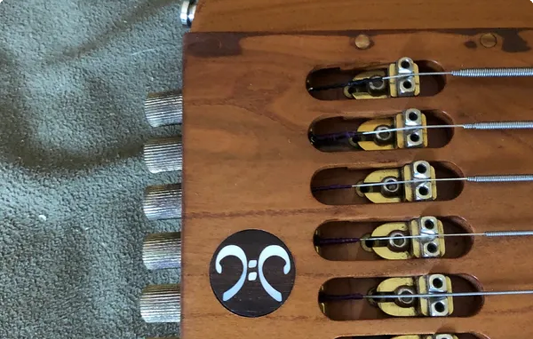 Wooden string instrument bridge with tuning pegs